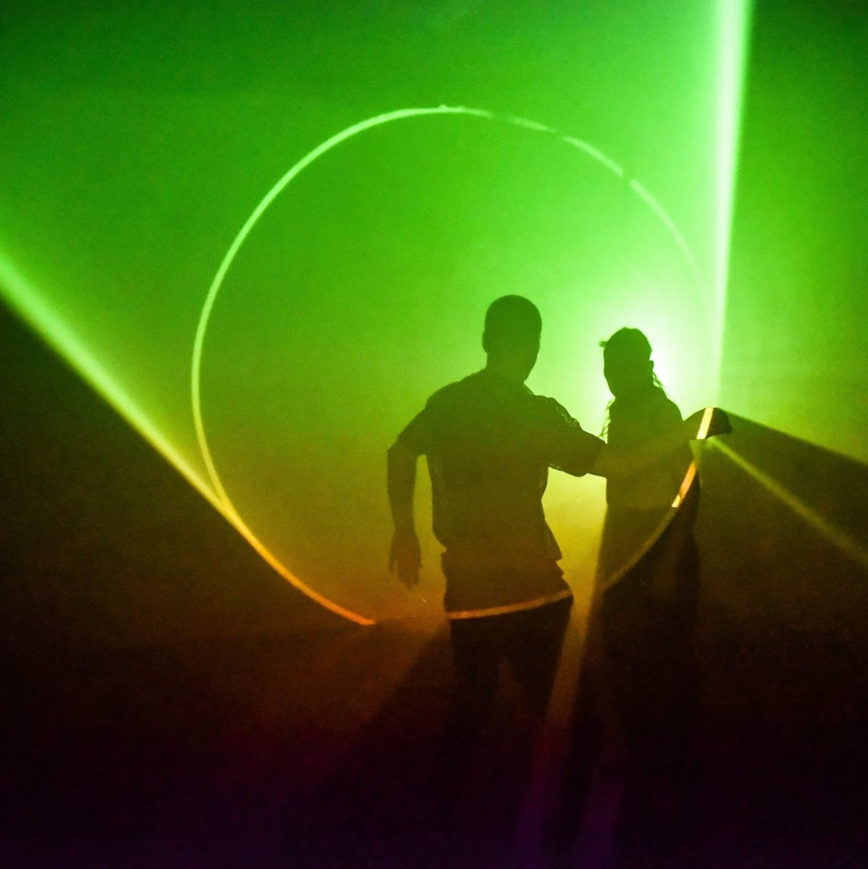 Two performers silhouetted within green stage lighting
